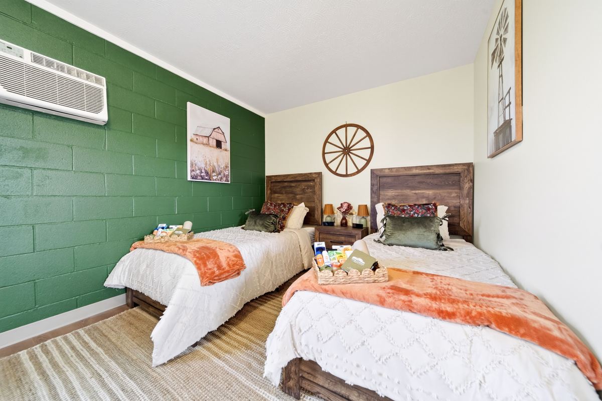 Two twin beds with wooden headboards, white quilts and rust throws in a resident bedroom